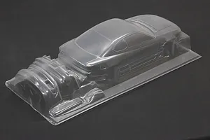 Unpainted clear polycarbonate RC car body shell of an S13 Silvia with molded parts set on a dark surface.
