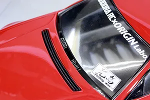 Close-up view of a red RC car body bonnet and windshield with Pandora RC and Origin Labo stickers.