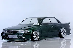 Pandora RC C33 Laurel 7800 painted dark metallic green RC drift car body shell on a white studio floor.