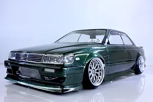 Low angle studio shot of a painted metallic green RC drift car body shell mounted on a chassis with deep dish wheels.