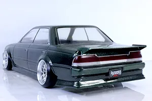Rear three-quarter view of a dark green metallic RC drift car body shell with custom wheels and a Pandora RC license plate on a white surface.