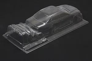 Clear unpainted polycarbonate RC car body shell on a black background, showing sedan profile and separate front bumper parts.