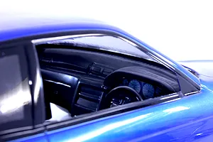 Close-up interior view of a blue RC car body showing the dashboard, steering wheel, and gauges through the side window.