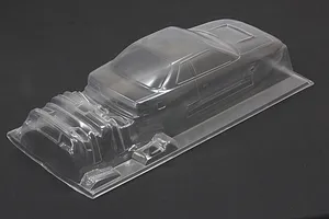 Unpainted clear polycarbonate RC car body shell with additional molded accessory parts on a dark background.