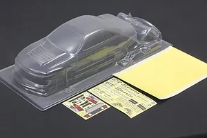 Unpainted clear polycarbonate RC car body shell with separate decal sheets and window masks on a dark surface.