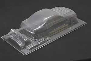 Unpainted clear polycarbonate RC car body shell on a dark surface, showing rear and side profile.