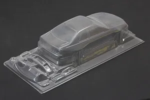 Unpainted clear RC car body shell with additional molded accessory parts set on a dark background.