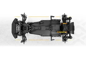 Top down studio view of an unpainted RC drift car chassis showing black plastic components, orange accents, and a foam front bumper.