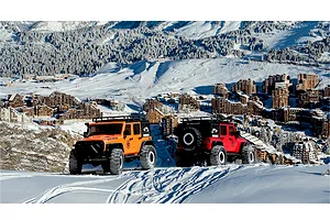 Two 1/10 scale RGT Rock Cruiser RC rock crawlers in orange and red driving on snowy mountain slopes.