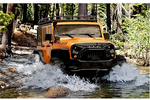 Orange RGT Rock Cruiser RC rock crawler driving through a shallow stream in a forest.