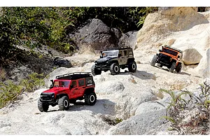 Three RGT Rock Cruiser Evolution V3 RC rock crawler models driving on rocky, sandy outdoor terrain.