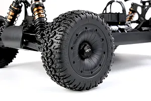 Close up view of the black wheel, chunky tread tyre, and suspension setup on a Rovan 1/5 scale RC buggy.