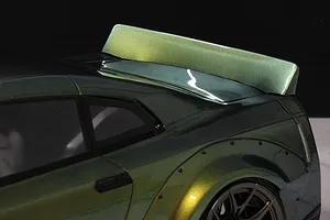 Close-up of a Pandora RC ducktail spoiler installed on the rear of a green and gold metallic RC drift car body.