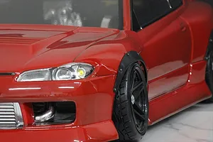 Close-up of a red RC car body showing the front fender flared wheel arch installed over a wheel and tire.