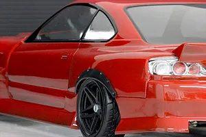 Close-up of a red RC car body showing the rear wheel arch fitted with a black over fender set