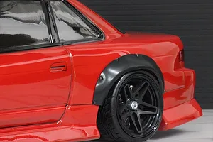 Close-up of a red RC drift car body showing a black over fender installed over the rear wheel arch.