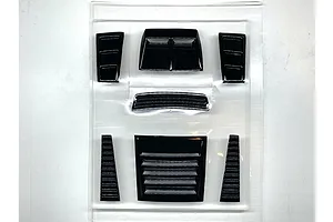Black plastic RC body shell duct and vent parts set in clear blister packaging on a white surface.