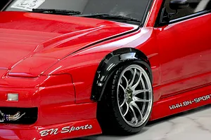 Close-up of a red RC car body shell installed with a black over fender set and chrome multi-spoke wheel.