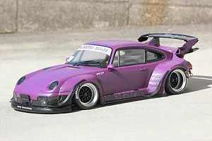 Purple RWB Porsche RC drift car body installed with wide fenders and large rear wing parked outside on concrete.