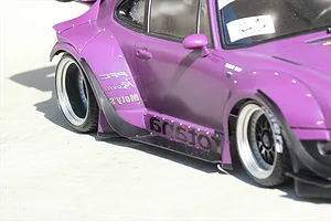 Close-up side view of a purple RC drift car body shell featuring wide fender flares and deep-dish wheels on a concrete surface.
