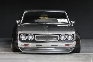 Front view of a custom grey RC drift car body showing overfenders and detailed grille against a dark background.