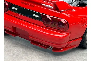 Close-up of the rear end of a bright red RC drift car body showing taillights, rear bumper, spoiler, and wheel.