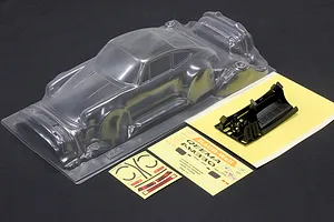 Pandora RC unpainted clear RWB 993 type body shell with decal sheets and black plastic parts on a dark surface.