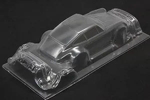 Unpainted clear polycarbonate RC car body shell of a widebody sports car on a dark surface.