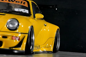 Close-up side profile of a yellow Pandora RC RWB 993 Type drift RC car body shell with wide fenders and a black wing.