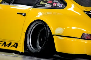 Close-up of the yellow RC car body showing the wide rear fender, deep dish wheel, and side decals.