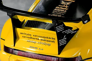 Close-up of the rear decklid and large black wing on a yellow Pandora RC RWB 993 body shell with decals.