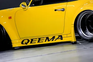 Close-up side view of a yellow RC car body showing the door, side mirror, wheel arch, and QEEMA decal.