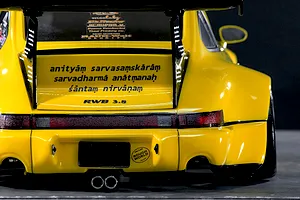 Rear view of a yellow Pandora RC RWB 993 body shell featuring a large rear wing, RWB 3.8 and Sanskrit text decals, and dual exhaust tips.