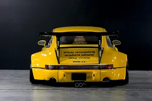Rear view of a yellow Pandora RC RWB 993 style body shell with wide fenders, large rear wing, and detailed decals.