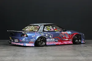 A custom RC drift car with a blue metallic body, rear wing, and numerous sponsor decals against a dark background.