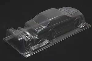 Unpainted clear polycarbonate RC car body shell on a black background, viewed from the rear three-quarters.