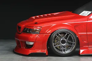 Close-up of the front left section of a red Toyota Cresta RC drift car body with custom wheel and vented hood against a dark background.