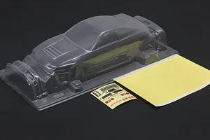 Unpainted clear polycarbonate Pandora RC 180SX Kouki body shell with included decal sheets and window masks on a dark surface.