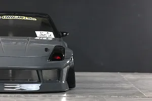 Front close-up view of a grey RC drift car body showing the front end, bumper, and tire against a dark background.