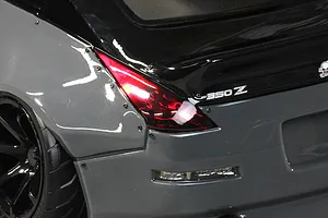 Close-up rear quarter view of a grey and black RC drift car body showing the tail light, 350Z badge, and wide fender flare.