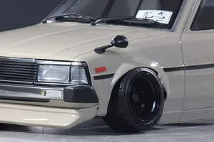 Close-up of a beige RC car body featuring front fender-mounted side mirror, black grille, and detailed wheel.