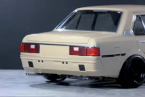 Rear-quarter view of the Pandora RC Toyota Corolla KE70 body shell in beige, showing taillights, dual exhaust, and black wheels.