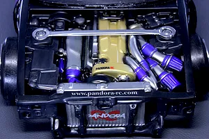 Detailed scale model RC car engine bay installed in a chassis with a gold valve cover and Pandora RC branding.