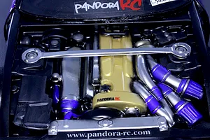 Detailed top-down view of a Pandora RC scale model engine bay with gold valve cover, strut bar, and intake details.