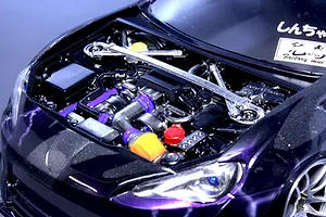 Detailed scale model engine bay installed inside a dark purple RC car body with a strut bar.