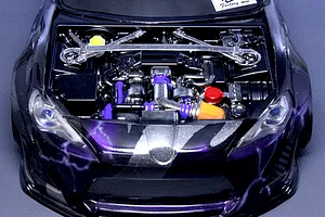 Detailed model car engine bay accessory installed in a black and purple RC car body with strut bar and aftermarket components.