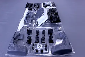 Unpainted RC car interior and accessory parts in a clear plastic vacuum-formed blister pack.