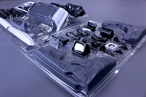 Unassembled plastic interior set parts in a clear blister pack for an RC car model on a grey surface.
