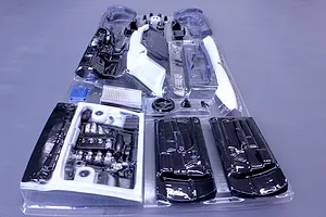 Unpainted plastic RC car interior and engine bay parts set in a clear vacuum-formed packaging tray.