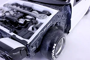 Close-up view of an RC car detailed engine bay and inner fender set installed in a white model body.